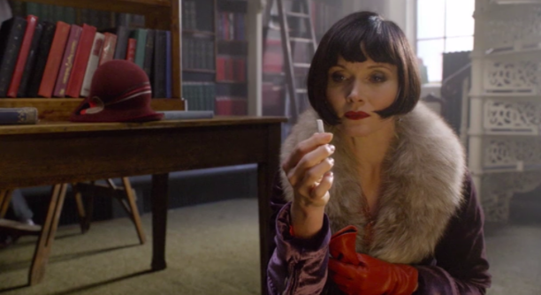 Screenshotted picture from Season One - Episode 5, “Raisins and Almonds”. Pictured: Miss Phyrne Fisher holding up a key piece of evidence.