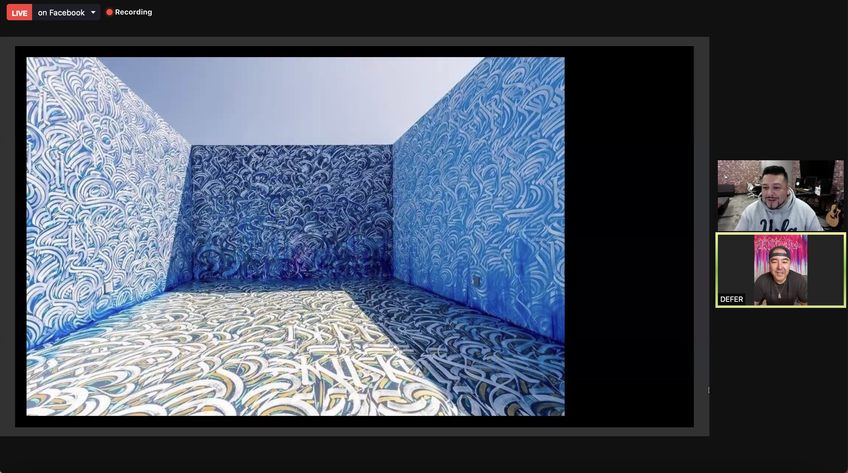 A screenshot of a zoom call shows two individuals, including artist DEFER. In the center of the screen is one of DEFER's works, a room filled with blue graffiti.